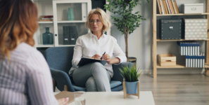 a woman sitting in a chair talking to another woman