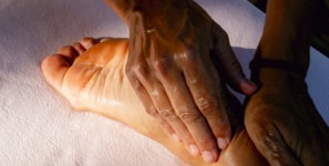 A person is doing a foot massage on a bed